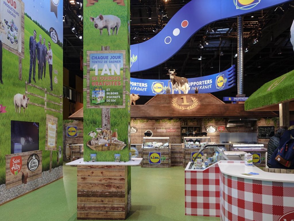 Conception de la scénographie pour Hopscotch de 2 stands pour Lidl au Salon de l'Agriculture de Paris. Le premier d'une surface de 300 m2 situé dans le hall 1 montrant les produits de la viande et du lait. Le second de 180 m2 dédié aux vins, fruits et légumes. La scénographie des stands est basé sur la thématique fournie qui est "Tous supporters du made in France". D'où le concept de "fermes" supportrices mêlant écharpes, médailles et podiums. Collaboration avec l'agence Hopscotch. Photos : Claude Lecante