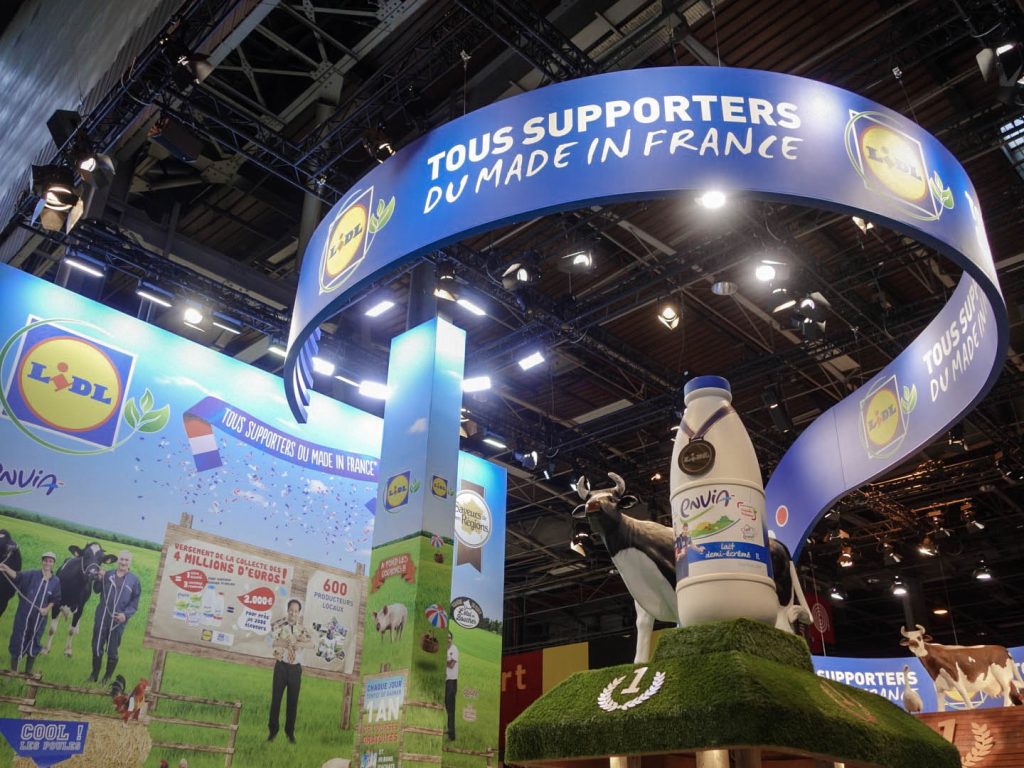 Conception de la scénographie pour Hopscotch de 2 stands 
pour Lidl au Salon de l'Agriculture de Paris.
Le premier d'une surface de 300 m2 situé dans le hall 1 
montrant les produits de la viande et du lait. 
Le second de 180 m2 dédié aux vins, fruits et légumes. 
La scénographie des stands est basé sur la thématique fournie 
qui est "Tous supporters du made in France". D'où le concept 
de "fermes" supportrices mêlant écharpes, médailles et podiums. 
Collaboration avec l'agence Hopscotch. Photos : Claude Lecante @lidl #lidl