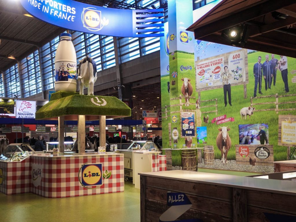 Conception de la scénographie pour Hopscotch de 2 stands pour Lidl au Salon de l'Agriculture de Paris. Le premier d'une surface de 300 m2 situé dans le hall 1 montrant les produits de la viande et du lait. Le second de 180 m2 dédié aux vins, fruits et légumes. La scénographie des stands est basé sur la thématique fournie qui est "Tous supporters du made in France". D'où le concept de "fermes" supportrices mêlant écharpes, médailles et podiums. Collaboration avec l'agence Hopscotch. Photos : Claude Lecante @lidl #lidl