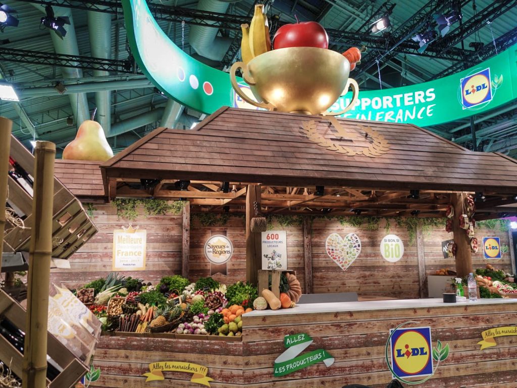 Conception de la scénographie pour Hopscotch de 2 stands pour Lidl au Salon de l'Agriculture de Paris. Le premier d'une surface de 300 m2 situé dans le hall 1 montrant les produits de la viande et du lait. Le second de 180 m2 dédié aux vins, fruits et légumes. La scénographie des stands est basé sur la thématique fournie qui est "Tous supporters du made in France". D'où le concept de "fermes" supportrices mêlant écharpes, médailles et podiums. Collaboration avec l'agence Hopscotch. Photos : Claude Lecante @lidl #lidl