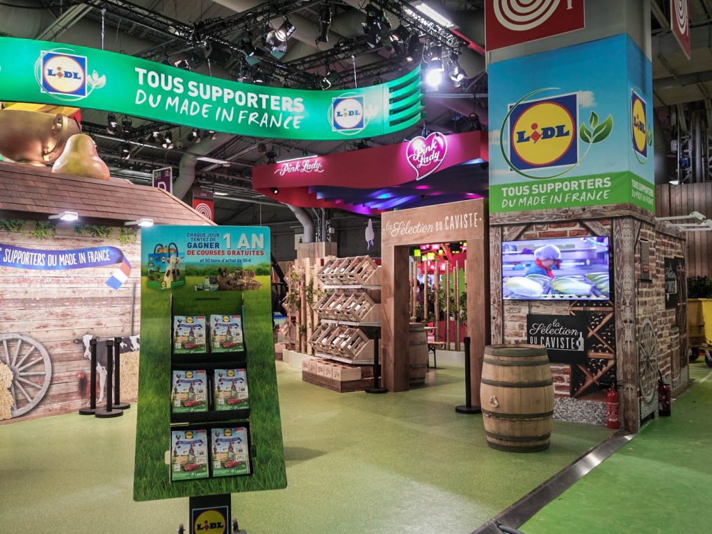 Conception de la scénographie pour Hopscotch de 2 stands pour Lidl au Salon de l'Agriculture de Paris. Le premier d'une surface de 300 m2 situé dans le hall 1 montrant les produits de la viande et du lait. Le second de 180 m2 dédié aux vins, fruits et légumes. La scénographie des stands est basé sur la thématique fournie qui est "Tous supporters du made in France". D'où le concept de "fermes" supportrices mêlant écharpes, médailles et podiums. Collaboration avec l'agence Hopscotch. Photos : Claude Lecante @lidl #lidl