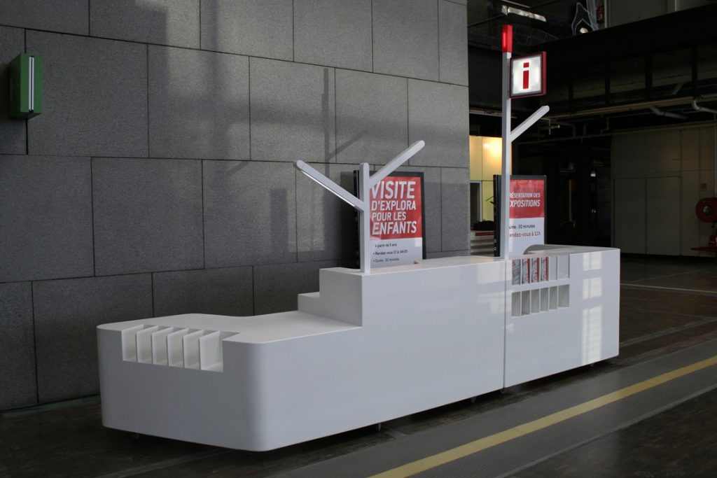 Réflexion sur les besoins, design pour une égonomie répondant aux besoins du public et de l’agent d’exploitation. La banque d’accueil est située au niveau Explora mais elle peut être facilement déplaçable dans l’ensemble de la Cité par le système de roues intégrées. Elle a pour vocation dans cet immense espace de renseigner et de distribuer des audioguides aux visiteurs. Conception, plans et suivi de fabrication. Réalisation en Corian. design Claude Lecante