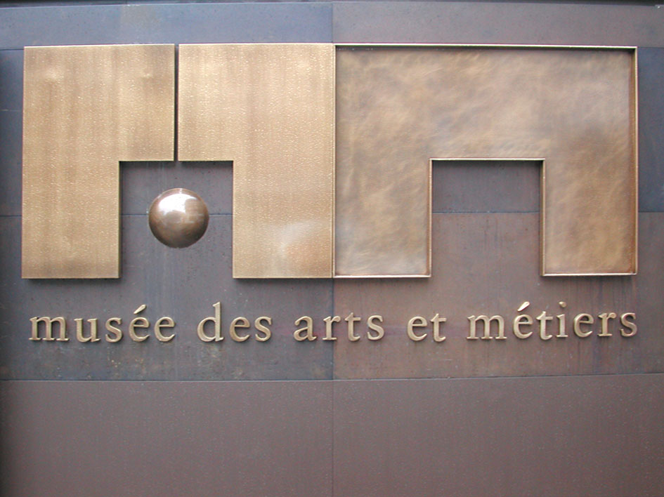 Assistance à Maîtrise d’Ouvrage pour l’ensemble de la signalétique. Mission de 4 mois sur site pour l’EPMOTC. Graphisme : Michel Bouvet Conception de supports en laiton pour les cartels présentés sur un socle (150 exemplaires réalisés). Étude pour la rénovation complète des deux modules d’entrée du musée. Recherche matériaux et nouveaux système d’éclairage. Plans et suivi de fabrication.